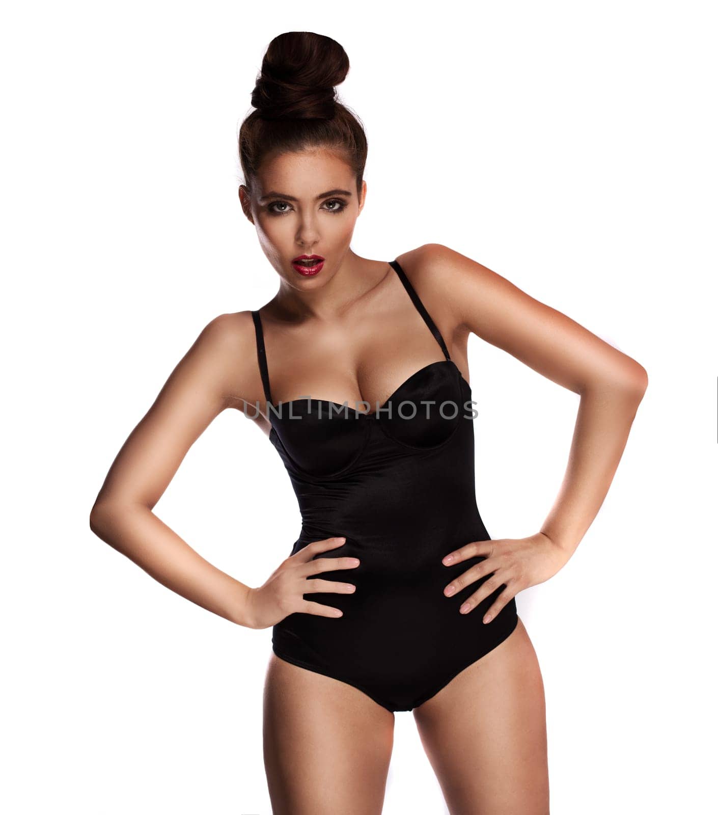Curvaceous beautiful woman in a swimsuit standing with her hands on her hips pouting provocatively at the camera