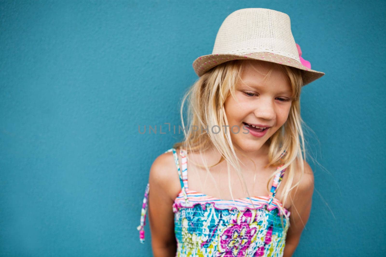 Portrait of stylish cute young girl smiling outside against blue wall background