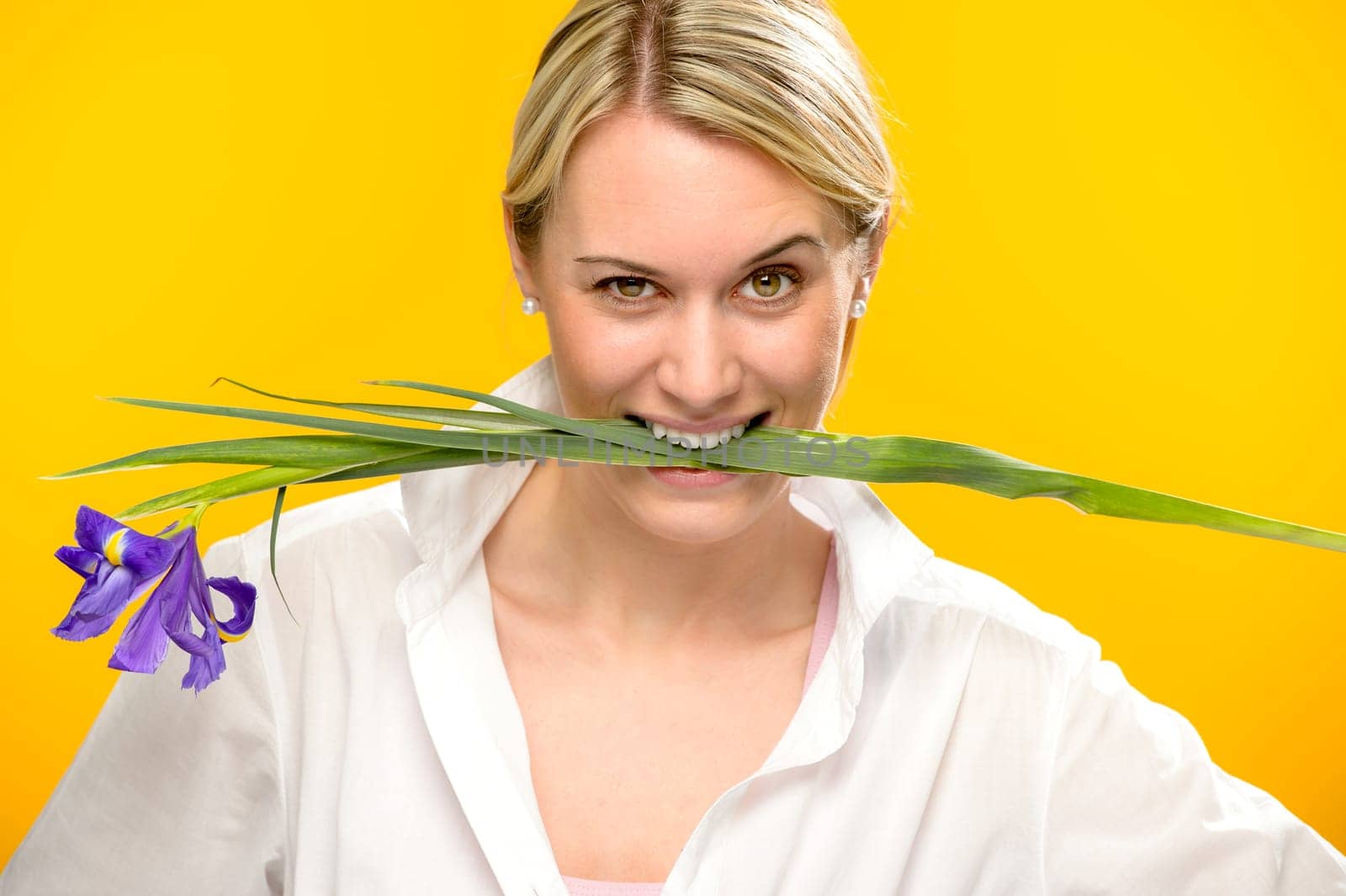 Woman with blue spring iris flower bite between her teeth