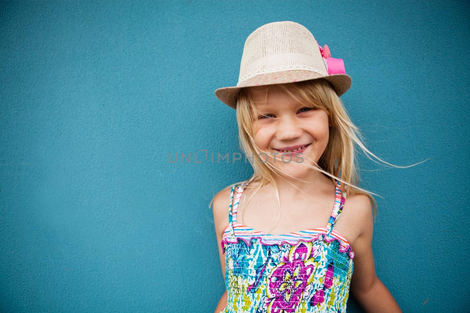 Portrait of stylish cute young girl smiling outside against blue wall background