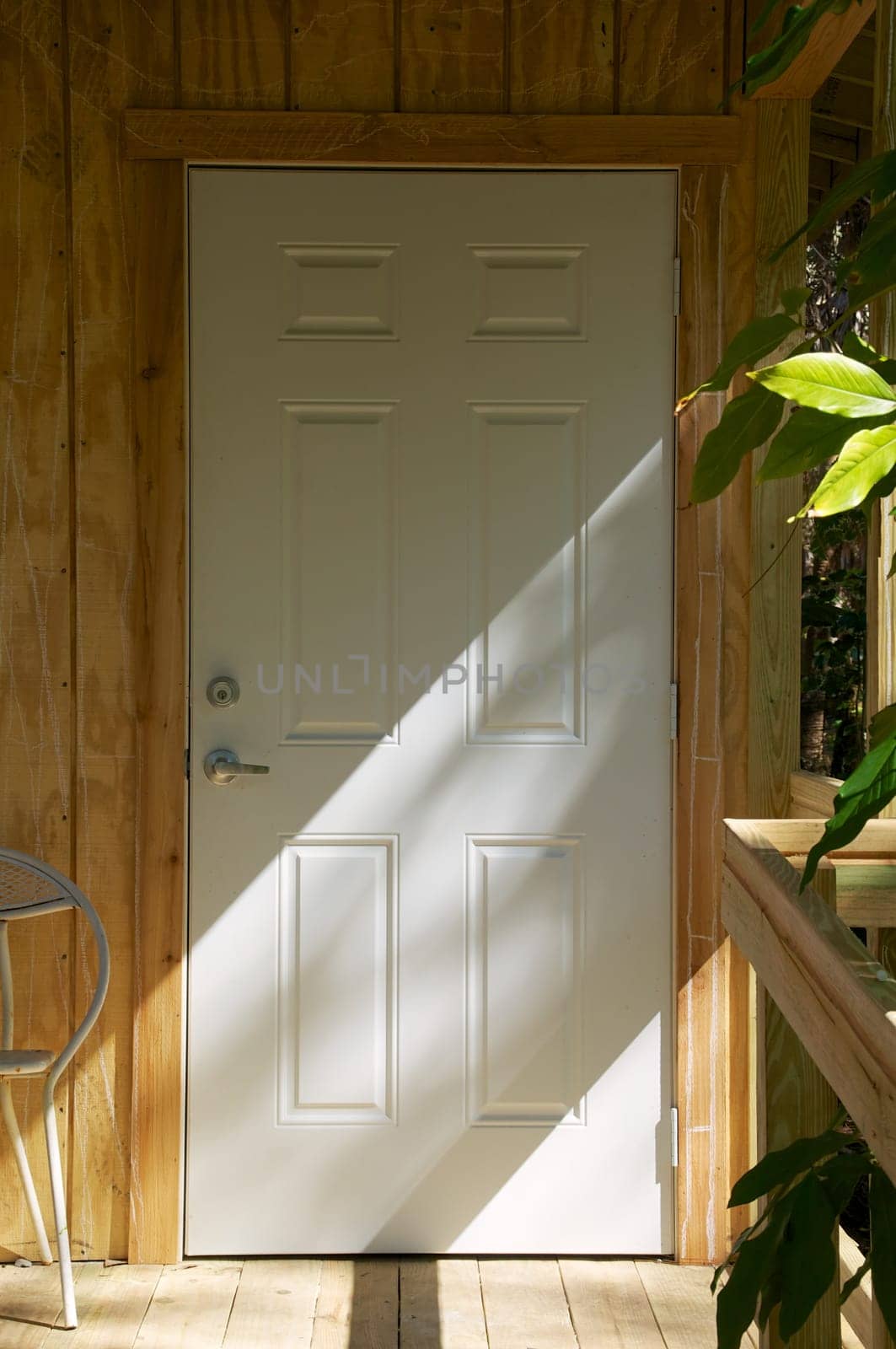 A closed door on exterior of newly constructed building, half in shade with diagonal sunlight.