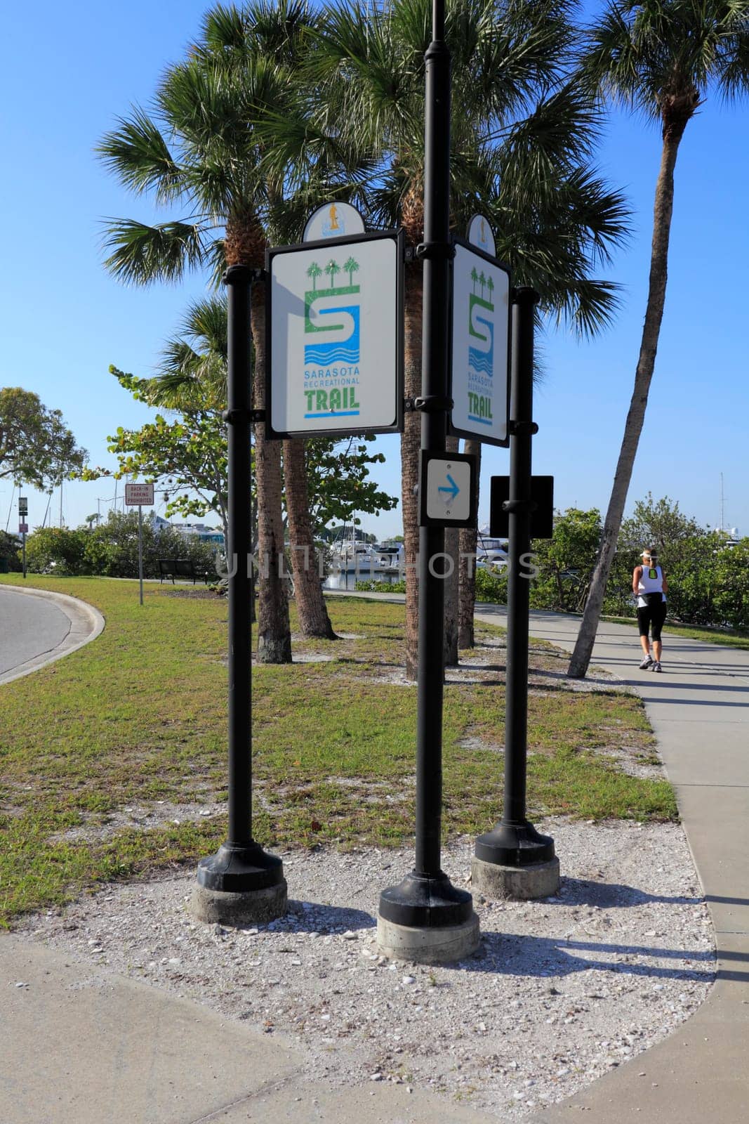 SARASOTA, FLORIDA - MAY 9, 2013: A woman getting healthy and fit with some early morning exercise by jogging the Bayfront Multi-use Recreational Trail sidewalk on a sunny, tropical day.