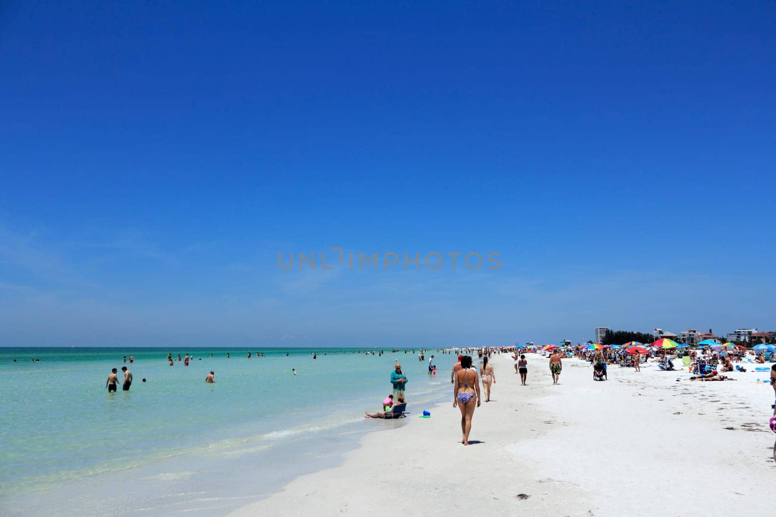 SIESTA KEY, FLORIDA - MAY 9, 2013: A colorful scene on a busy day with lots of people enjoying relaxing at the beautiful white quartz sand Siesta Beach, voted one of the best beaches in the world.