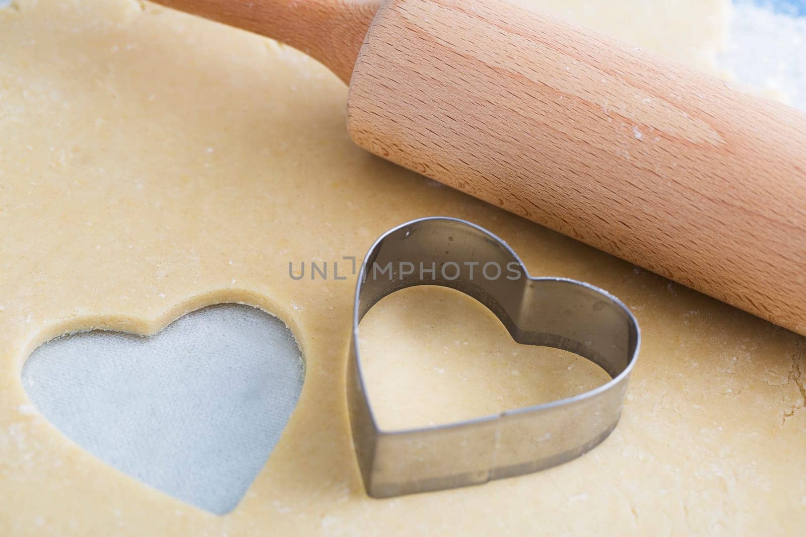 Dough rolled out with heart shape cut out, and heart shaped cookie cutter