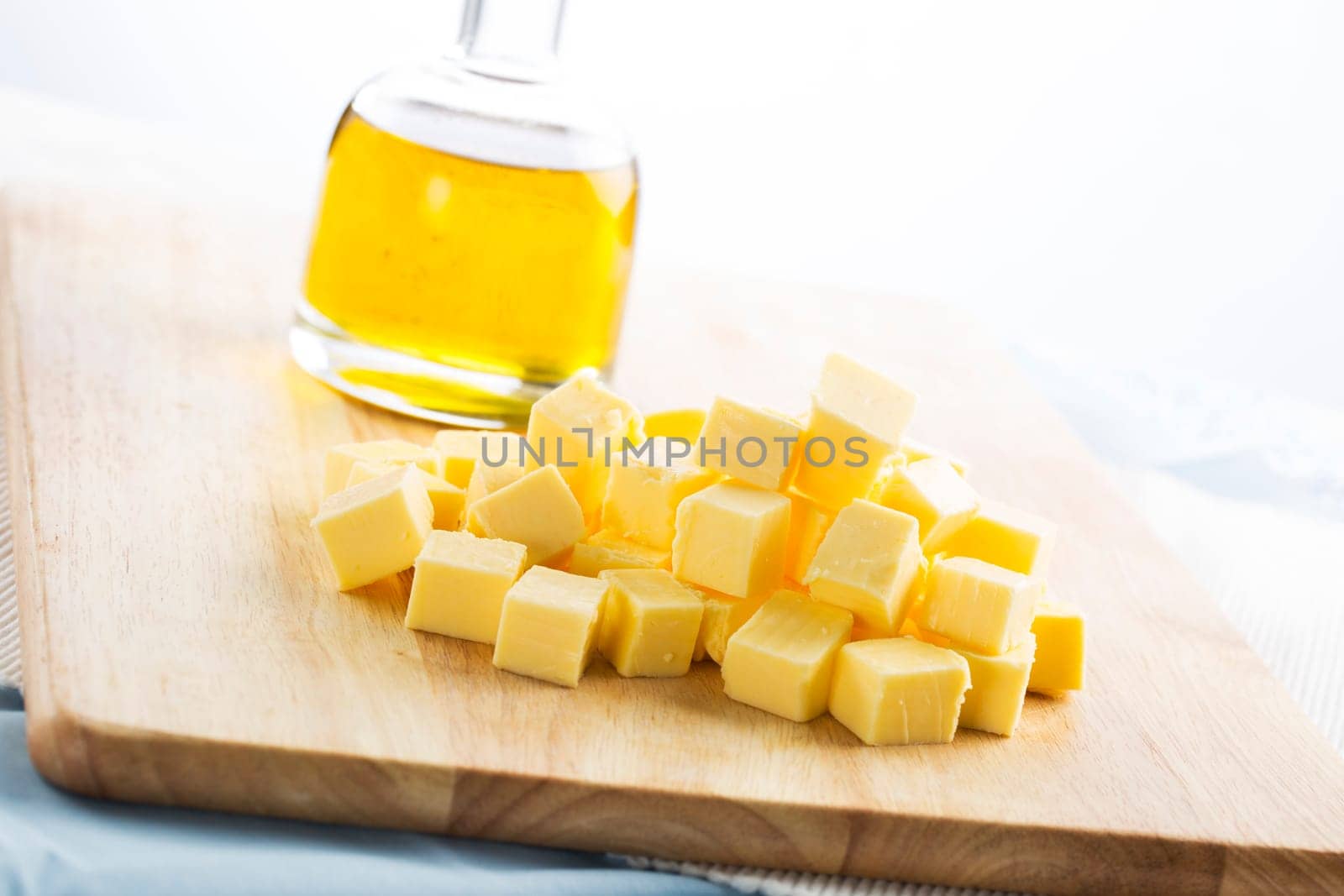 Butter pieces (cubes) on a cutting board, with bottle of vegetable oil in the background
