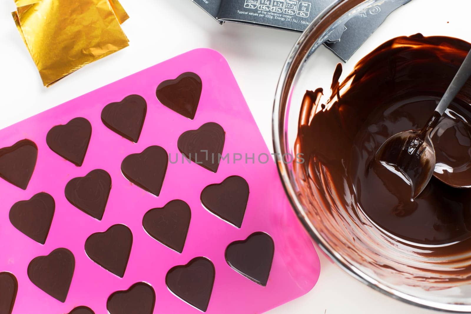 Bowl of warm chocolate and heart shaped form filled with chocolate.