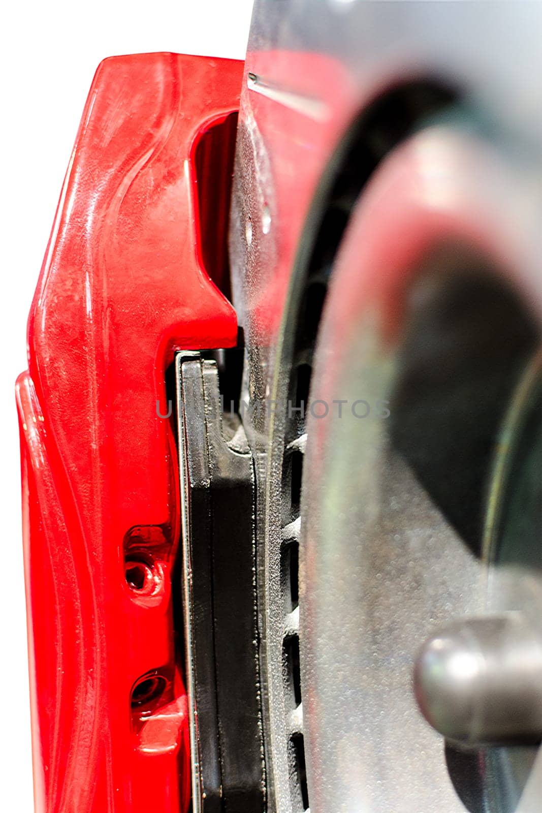 Closeup pads on disc car brake in red caliper isolated
