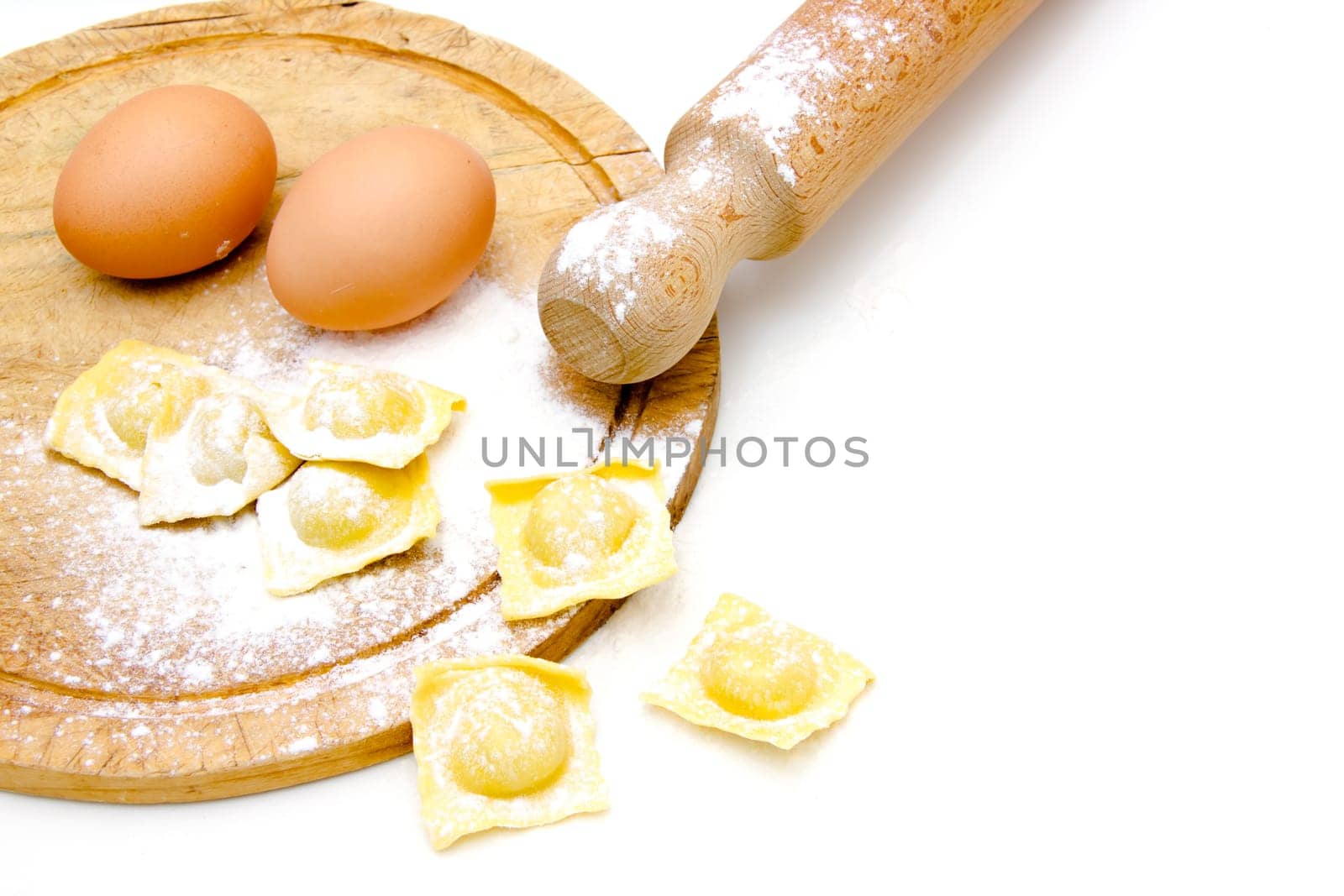 Ravioli on the cutting board and eggs on white background