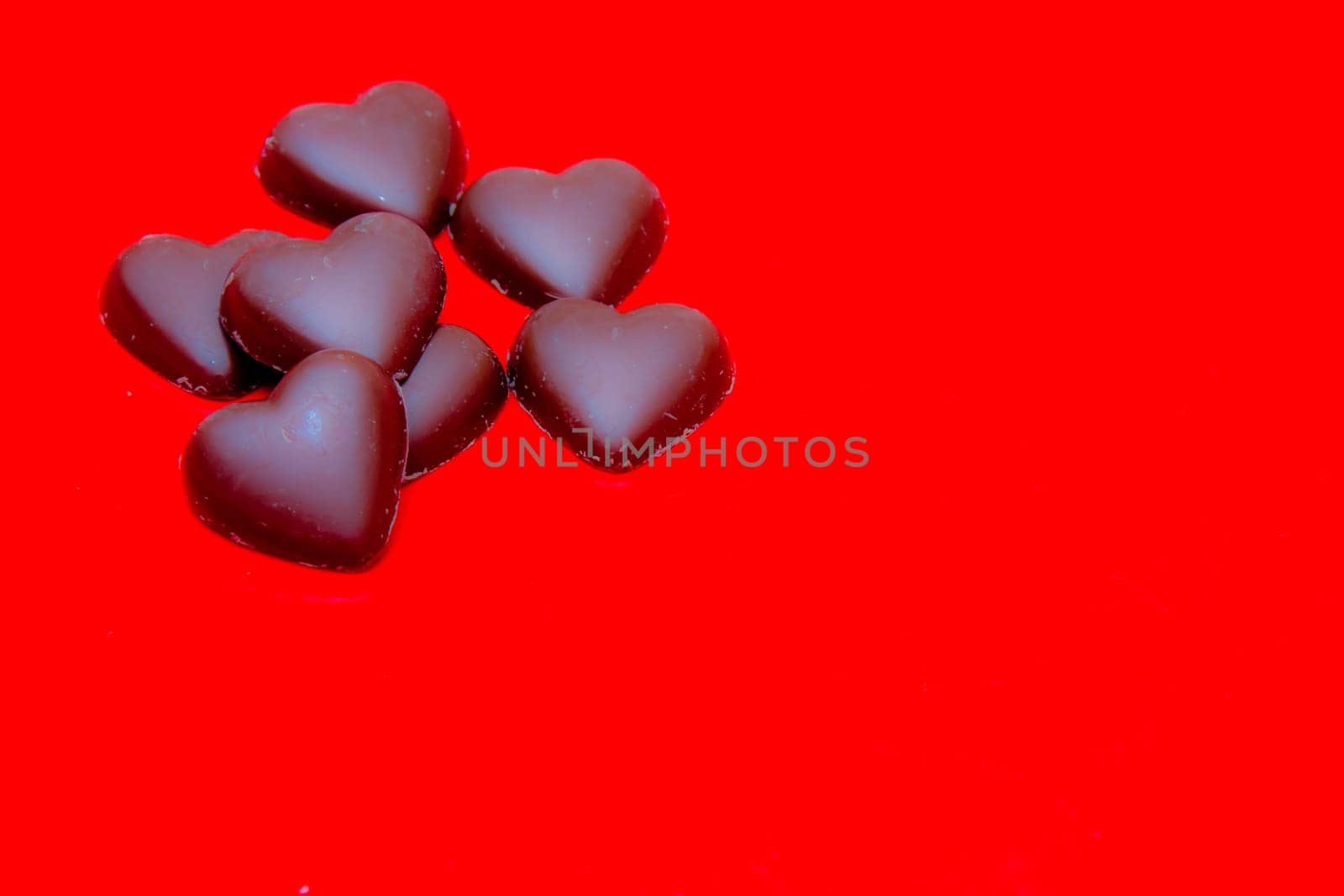 Chocolate hearts arranged on red background