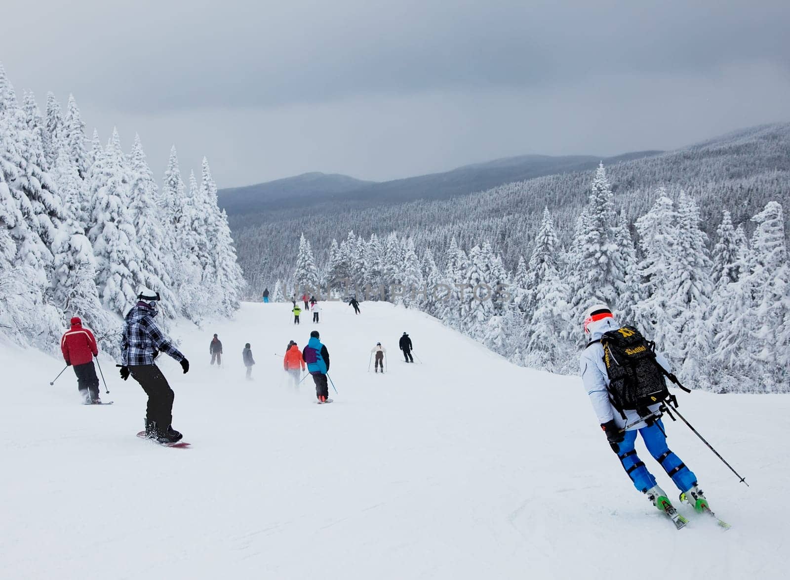 Mont-Tremblant , Quebec, Canada - February 9, 2014: Skiers and snowboarders are sliding down an easy slope at Mont-Tremblant Ski Resort. It is acknowledged by most industry experts as being the best ski resort in Eastern North America.