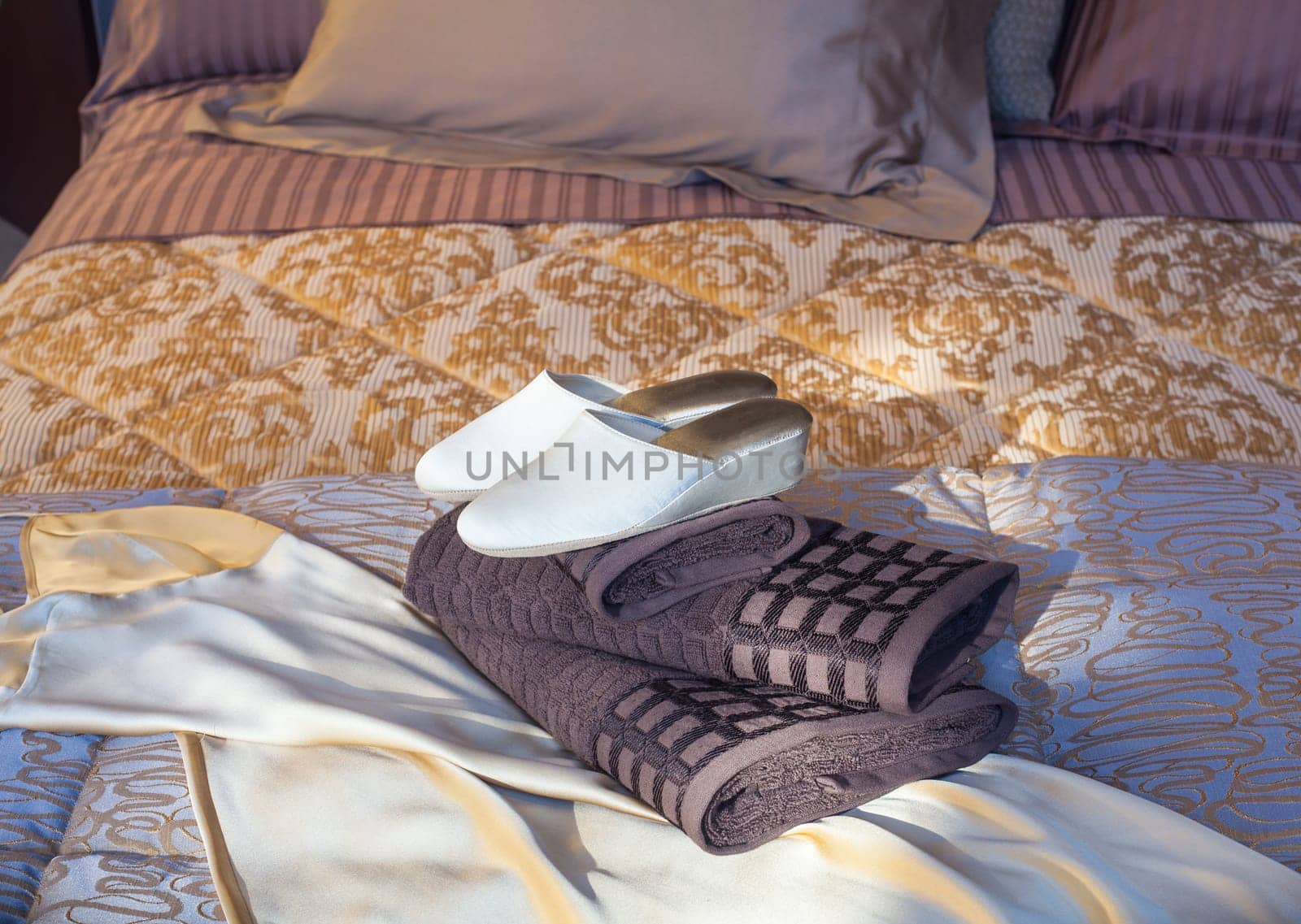 White female slippers on the towels in the bed