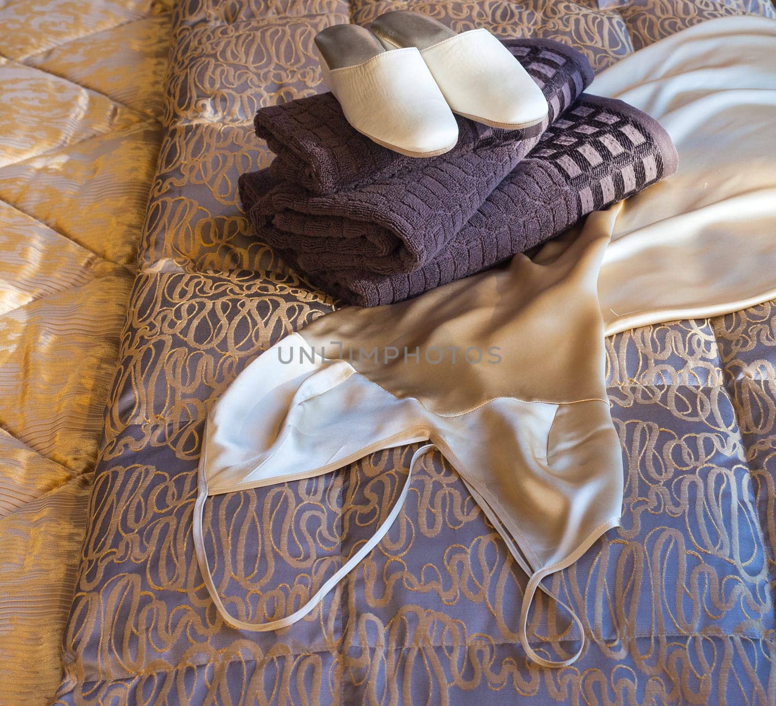 White female slippers on the towels in the bed