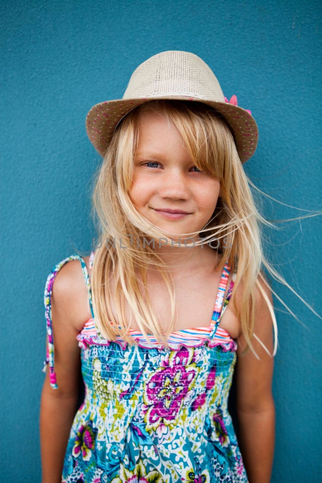Portrait cute happy young girl wearing stylish hat outside against blue wall background