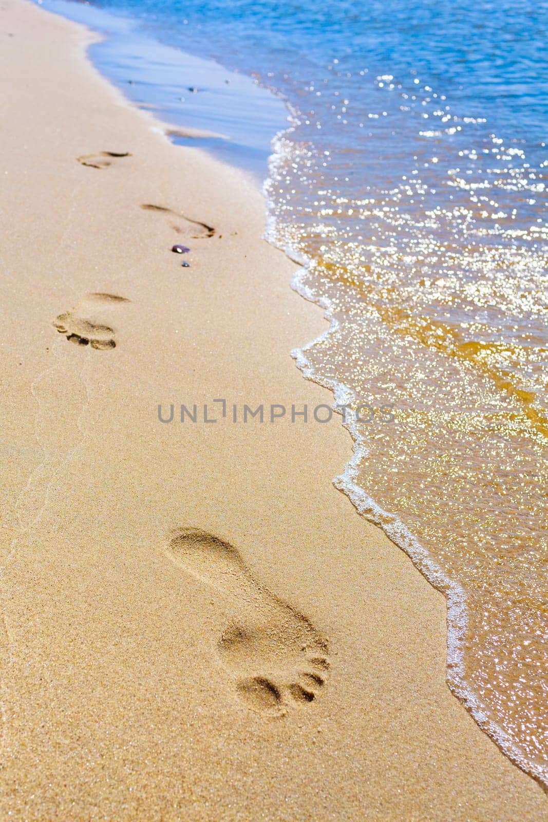 clear footprints on the beach by the sea,visible yellow sand and blue sea.