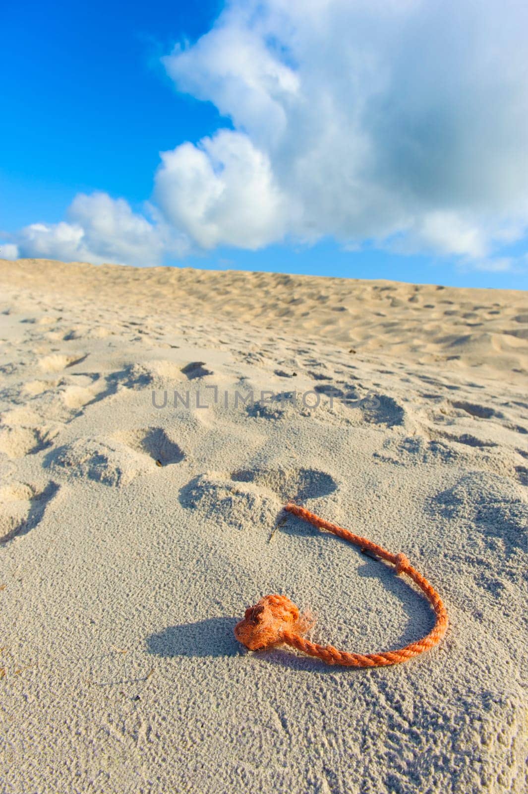 A fragment of the net rope on the beach, sky and white and grey clouds in the background.