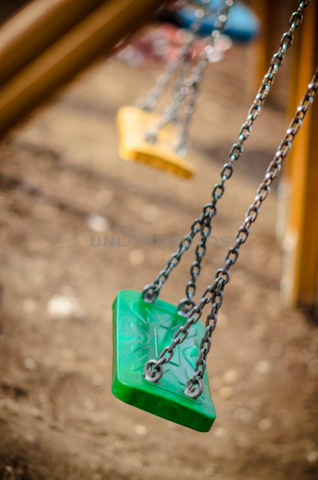 Abandoned autumn, fall playground, with green swings and yellow swings in the background, chain swings.