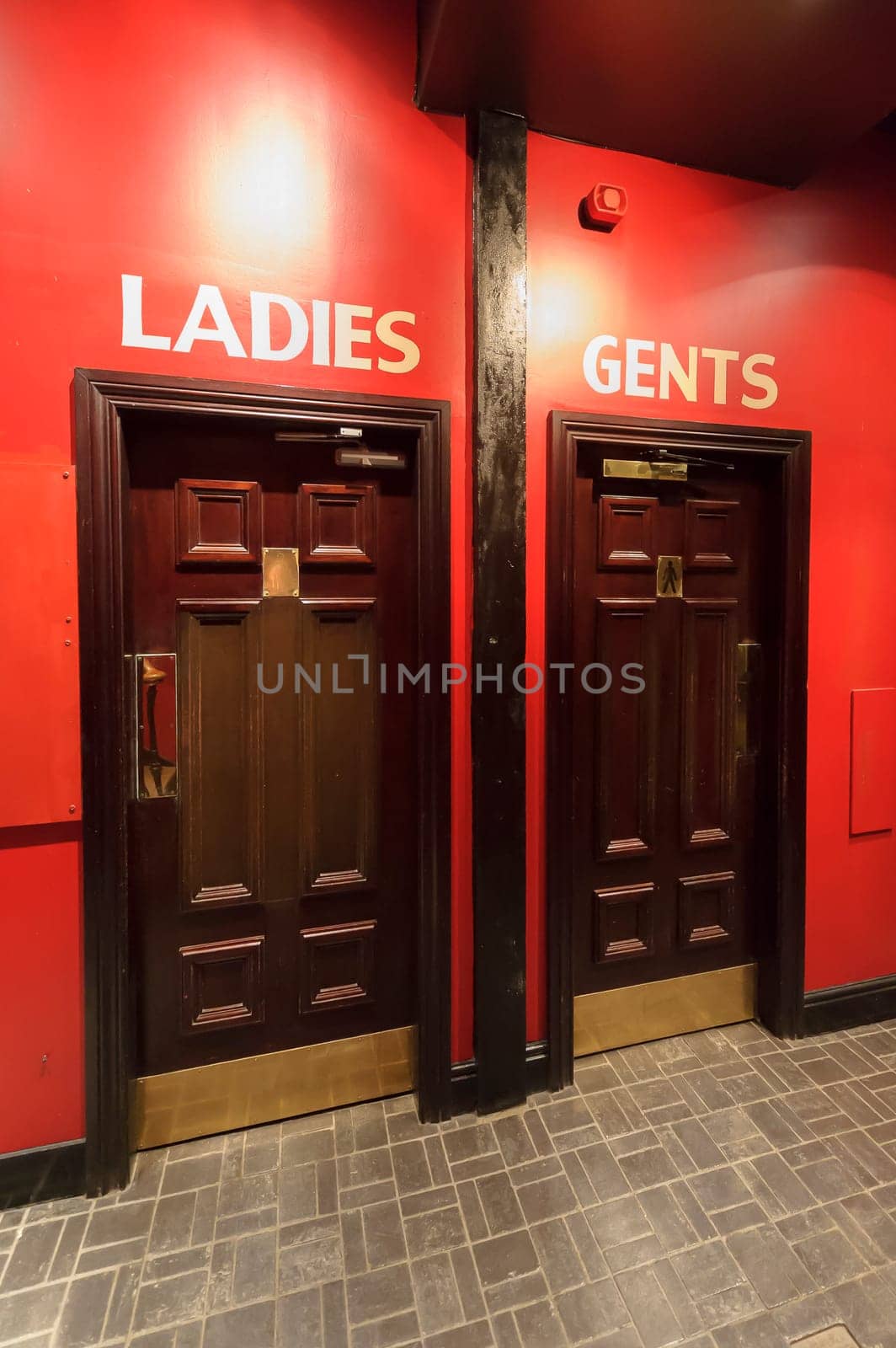 Entrance to the WC,  toilets in the restaurant, separate for ladies,women and gents,menon the red wall, dark brown door.