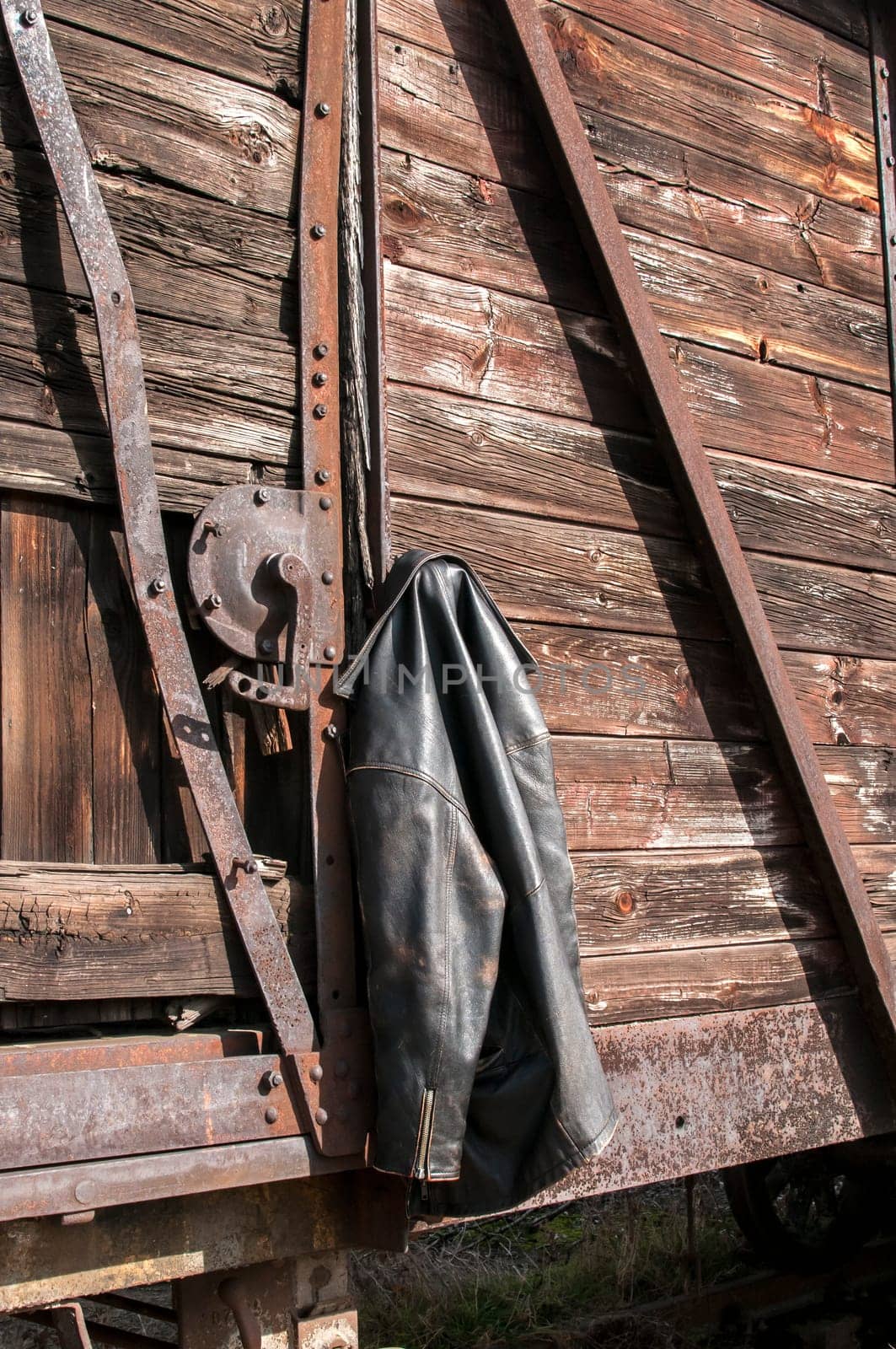 Vintage leather male jacket hanging on the wall of old wooden railway wagon as background
