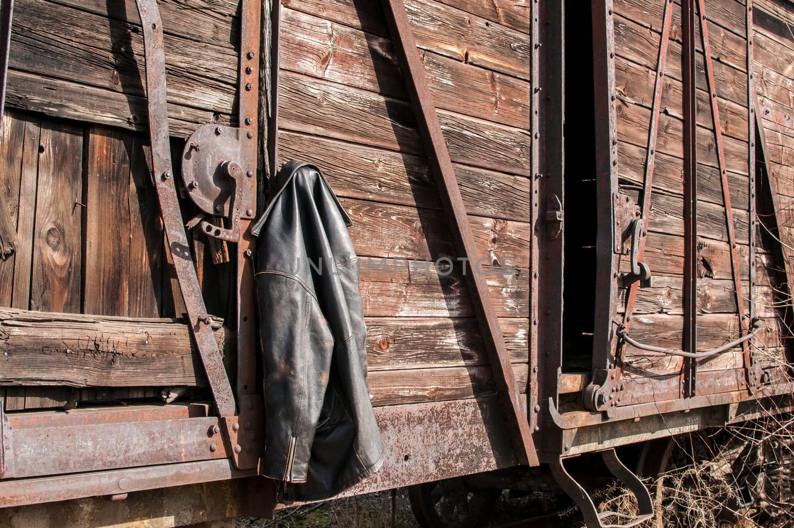 Vintage leather male jacket hanging on the wall of old wooden railway wagon as background