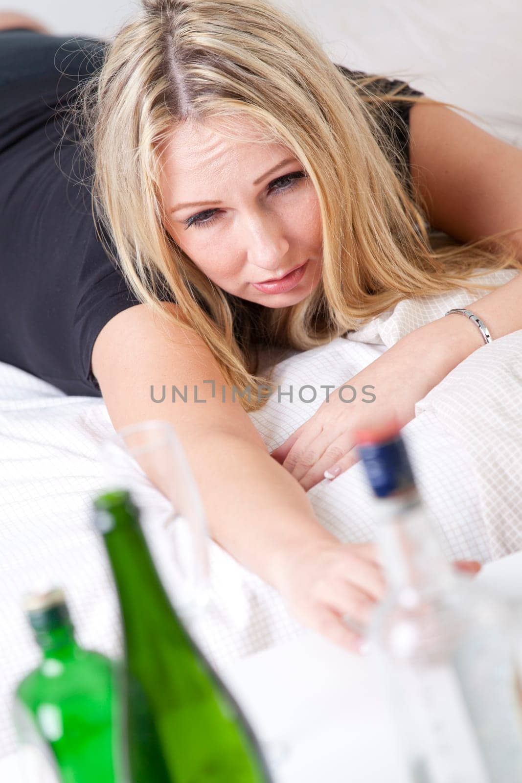 woman alcoholoism addiction - woman in bed reaching for the bottle