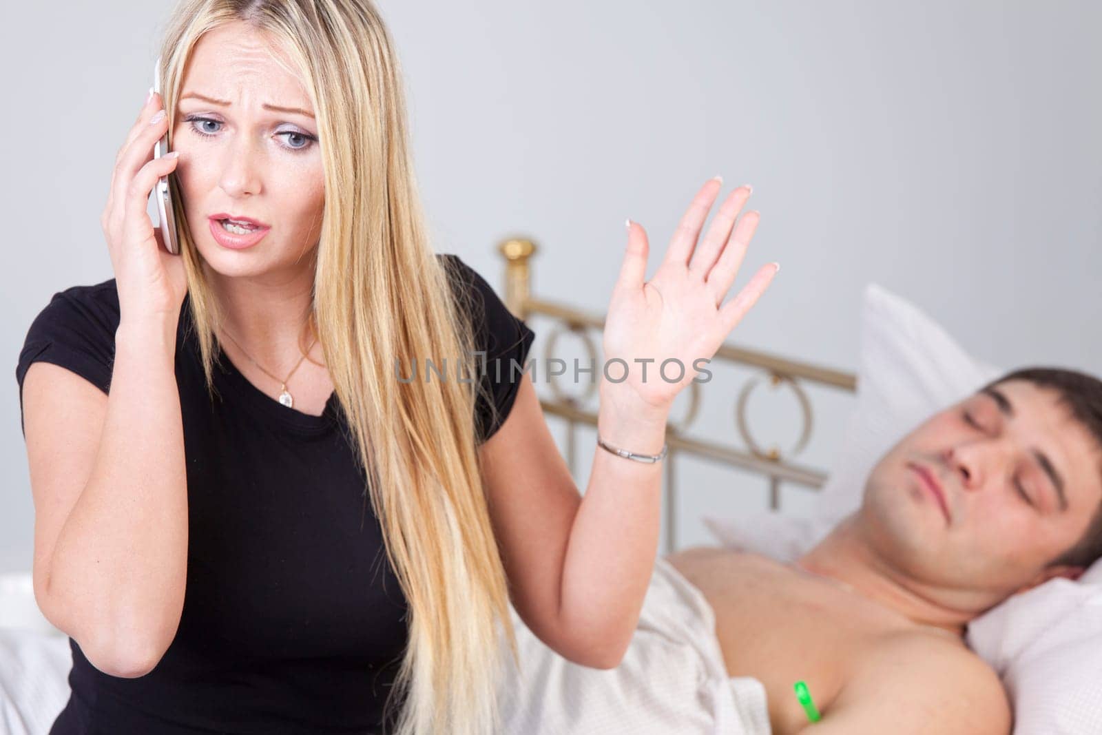 Worried woman makes a emergency call while sick man lying on bed