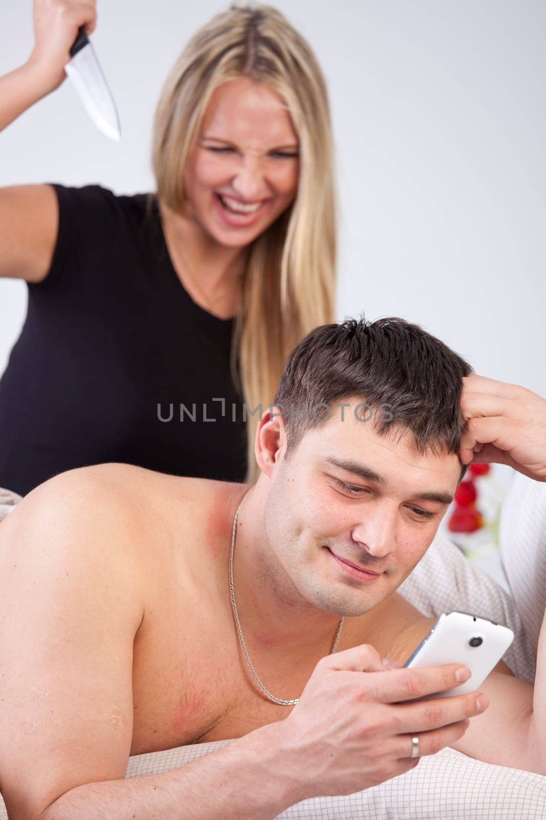 Man is cheating on phone, angry woman with knife behind him
