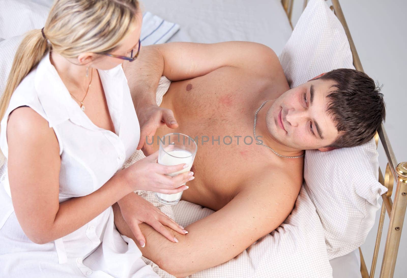 Woman in white coat caring sick man with a milk