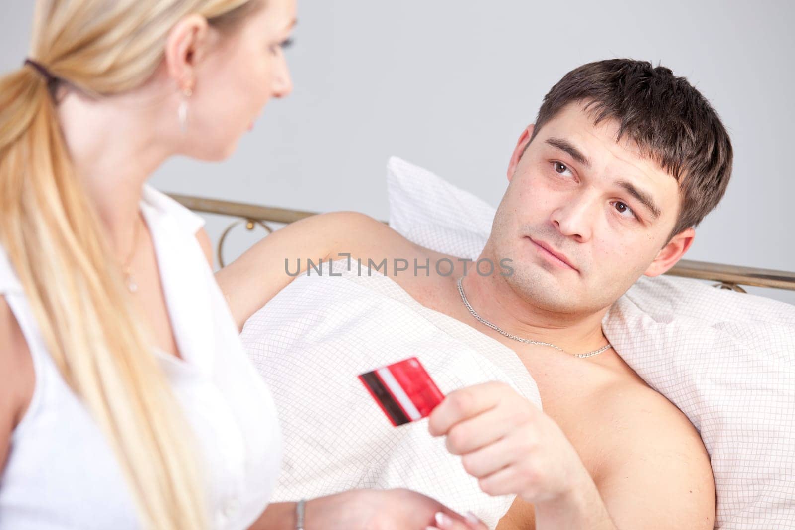 Man in bed holding credit card - paying for medical treatment or service