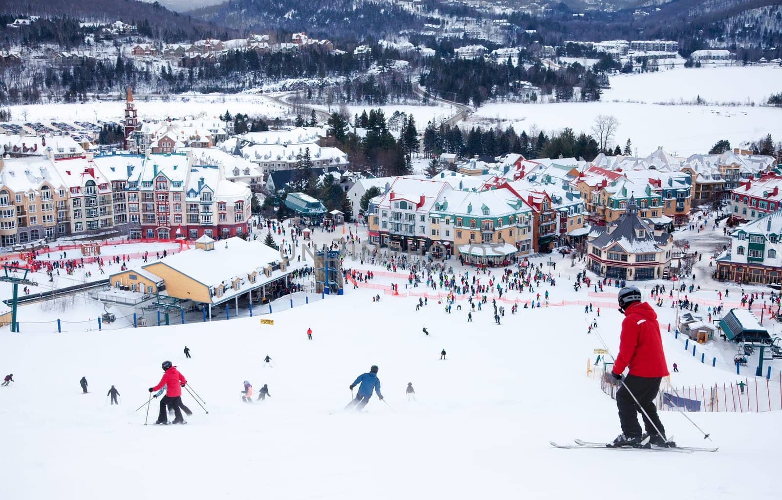Mont-Tremblant, Canada - February 9, 2014: Skiers and snowboarders are sliding down the main slope at Mont-Tremblant. Mont-Tremblant Ski Resort is acknowledged, by most industry experts, as being the best ski resort in Eastern North America.