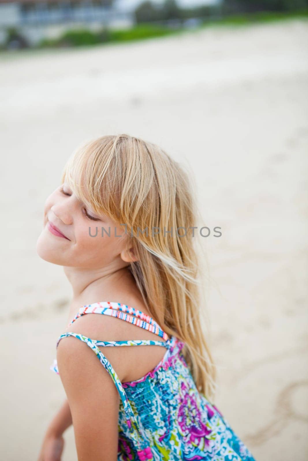Cute smiling young girl at the beach with eyes closed
