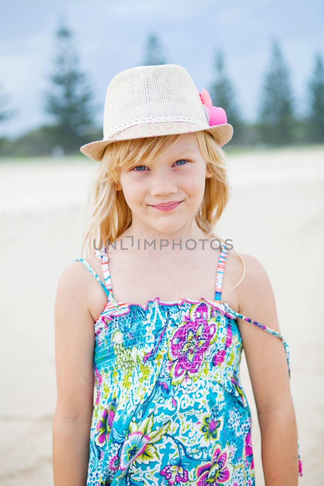 Portrait of cute young girl with summer dress and stylish hat at the beach