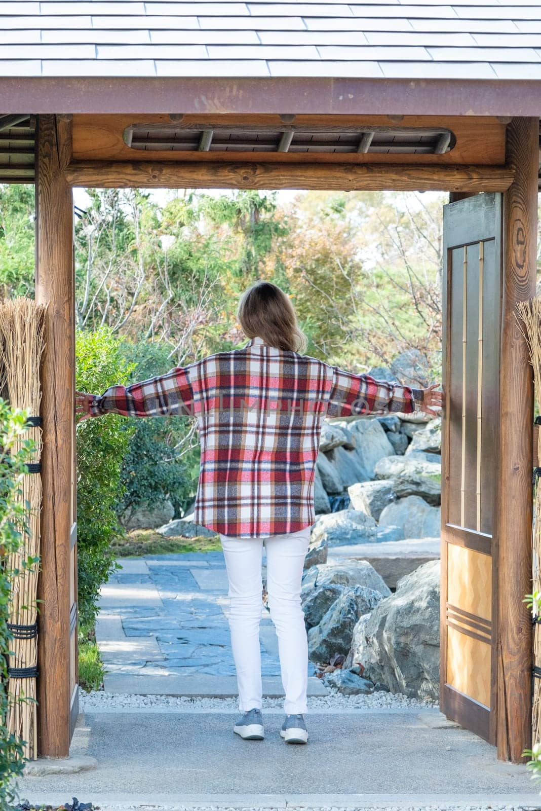 Woman in red plaid shirt enjoying nature walking in Japanese Garden