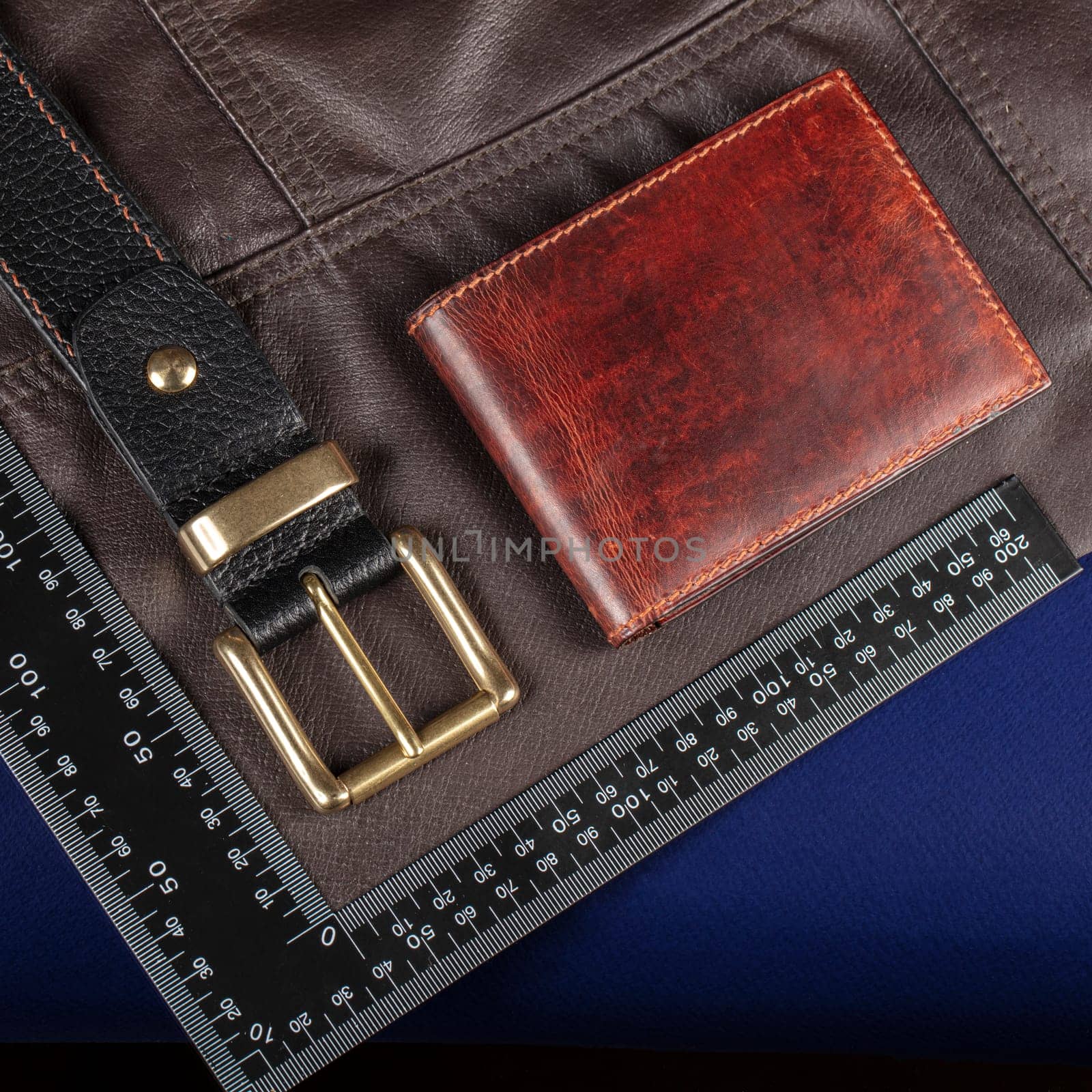 Leather goods purse and belt against the background of a ruler for cutting and sewing.