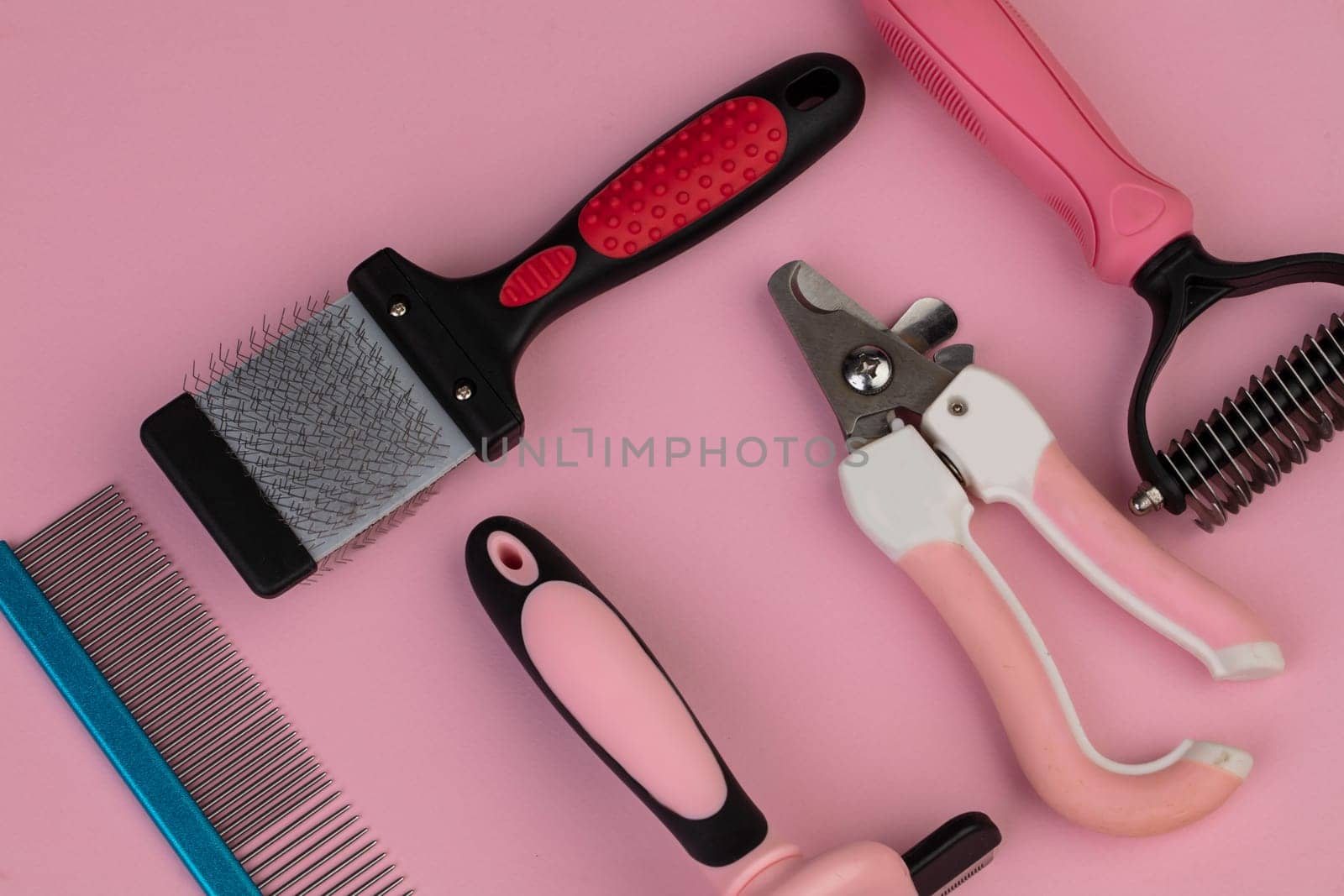 Tool for the groomer on a pink background. Dog grooming accessories. Combs and brushes for animals. View from above