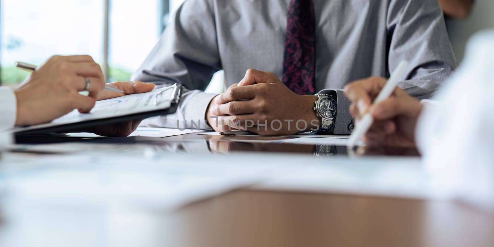Focused executive businessman client clasped hands negotiating, thinking, making decision sitting at table listening manager partner at offic.