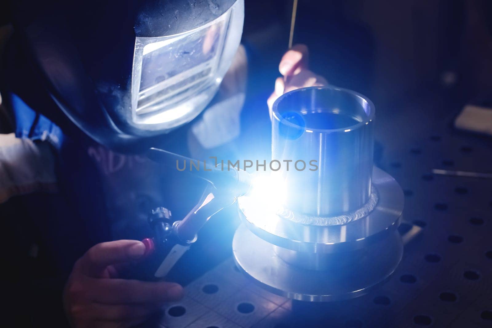 A professional welder plasma welds stainless flanges. Industrial background by yanik88