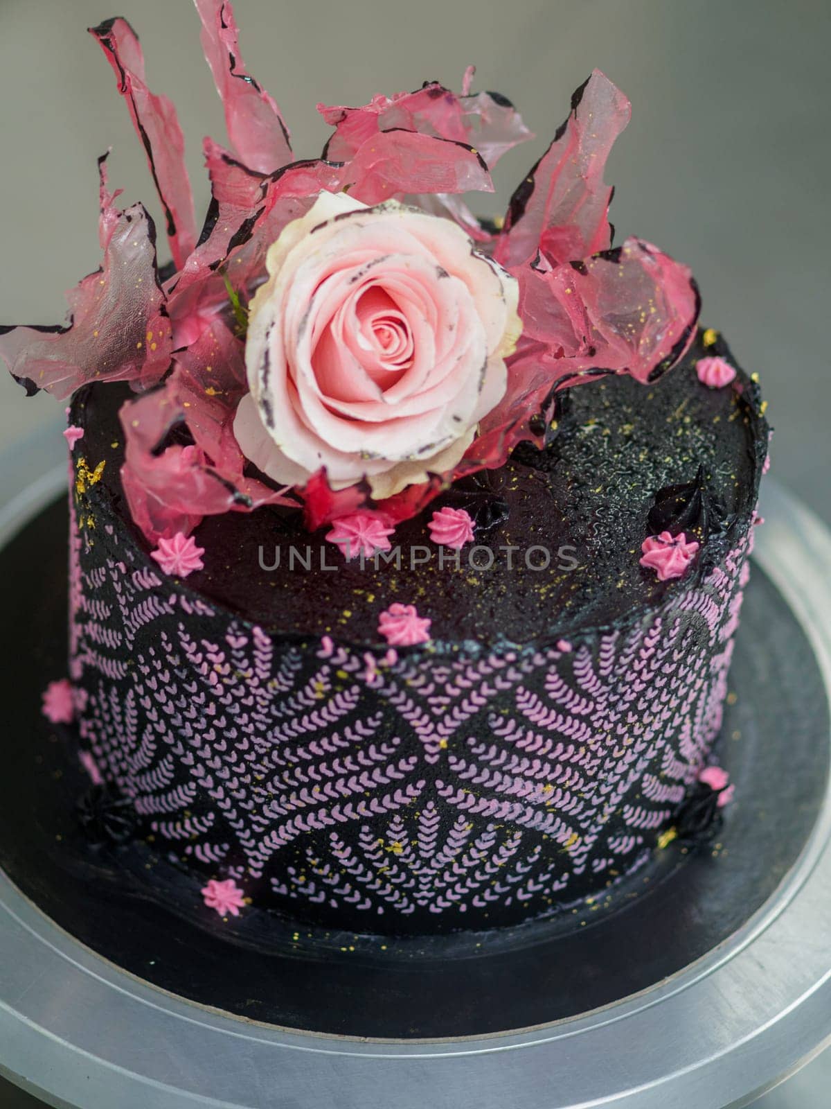 frosted icing black decorate cake for birthday celebration, real rose topping and pink sweet swirls by verbano