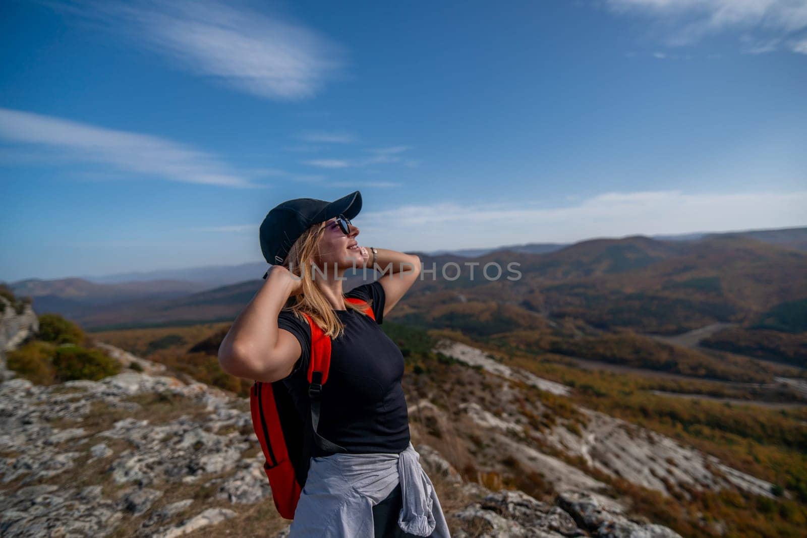 woman backpack on mountain peak looking in beautiful mountain valley in autumn. Landscape with sporty young woman, blu sky in fall. Hiking. Nature by Matiunina