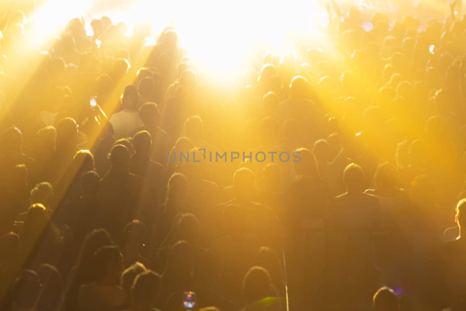 A concert crowd illuminated by bright yellow lights. by Studia72
