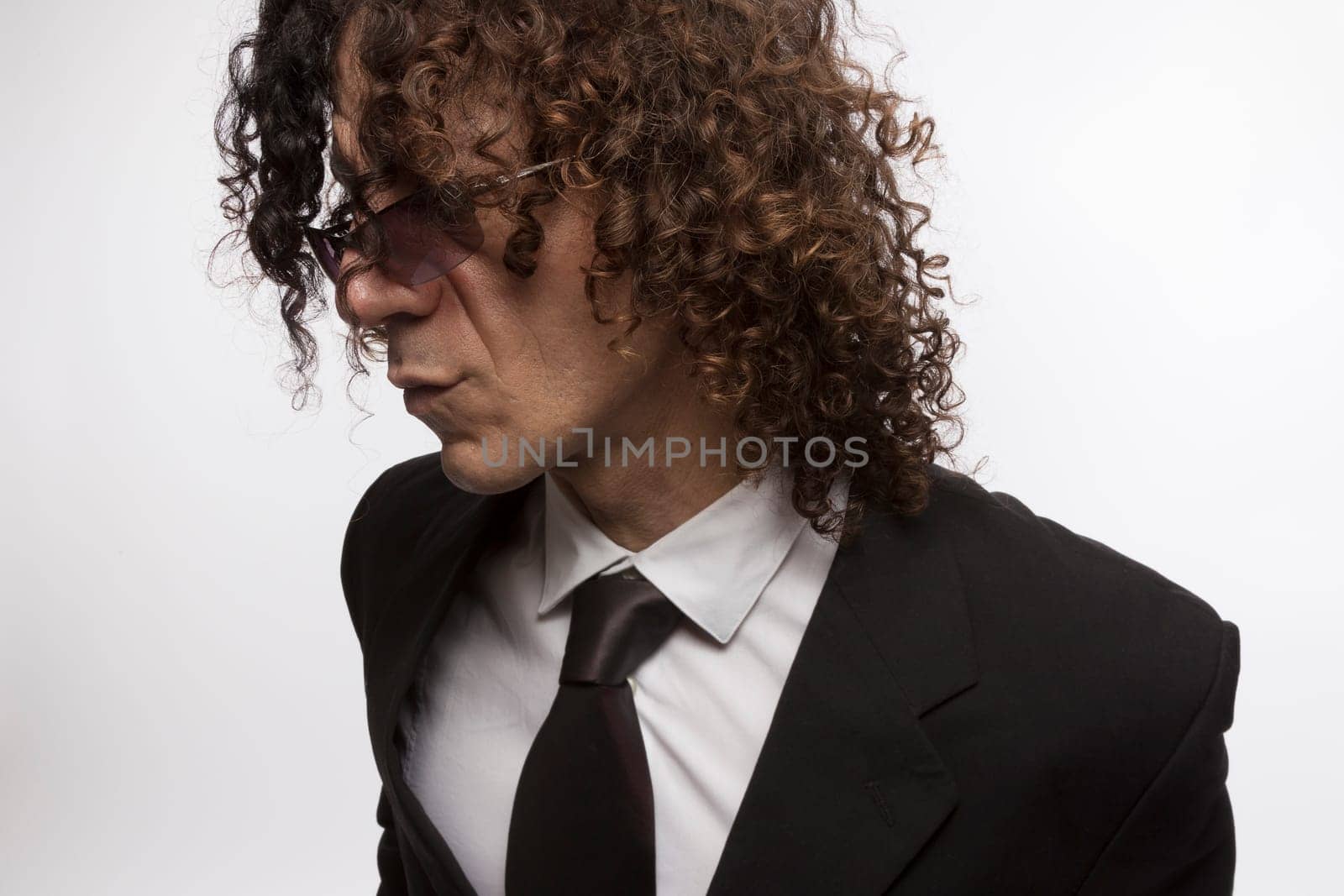 Cropped portrait of mediterranean looking man with curly hair wearing business suit and sun glasses
