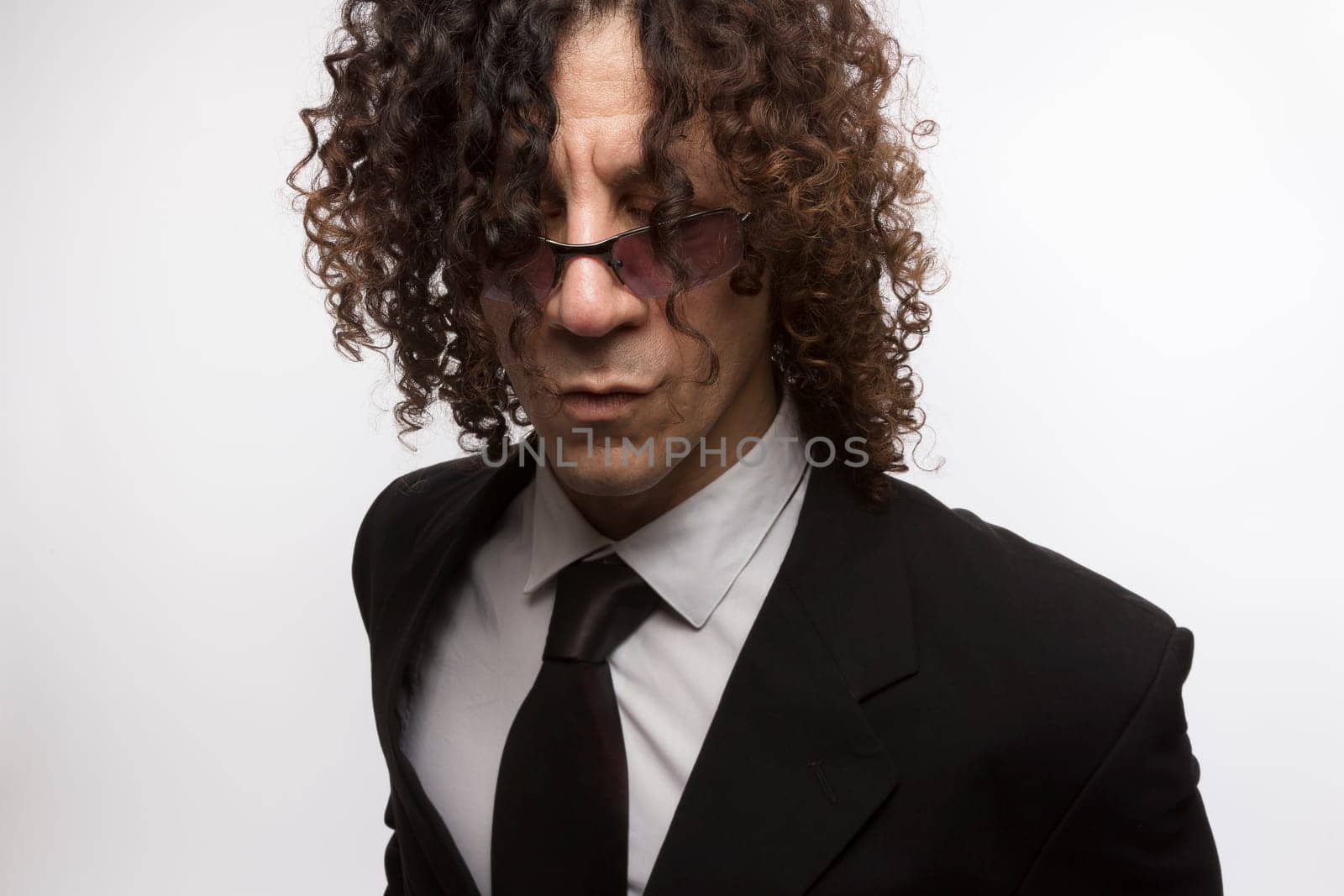 Cropped portrait of mediterranean looking man with curly hair wearing business suit and sun glasses