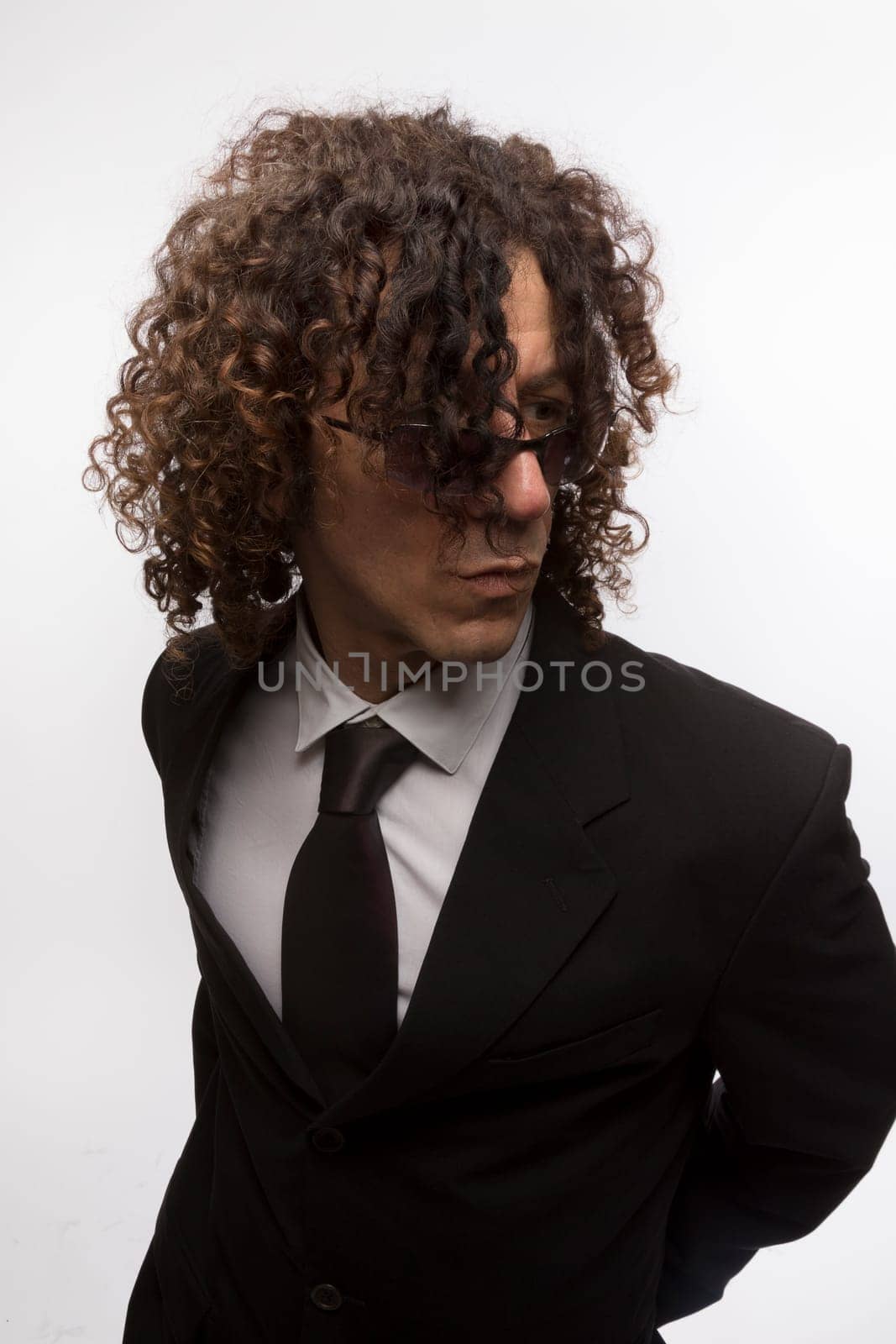 Cropped portrait of mediterranean looking man with curly hair wearing business suit and sun glasses