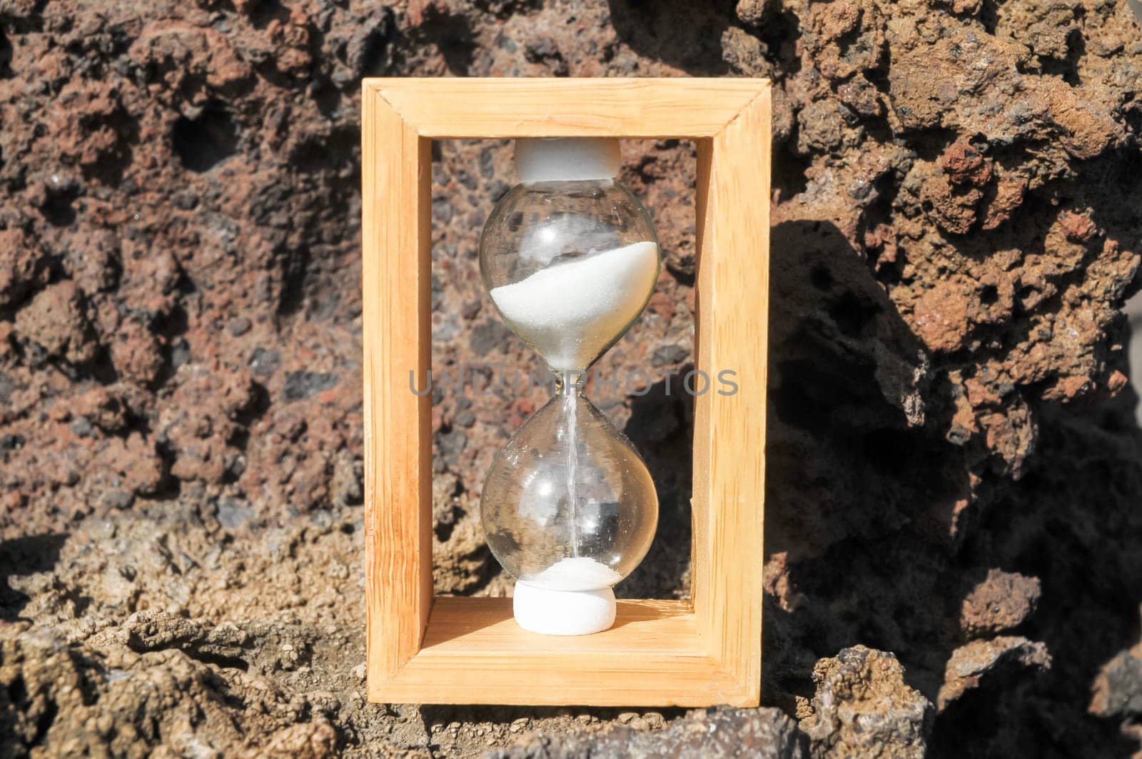 Time Concept White Sand Hourglass on the Volcanic Rocks