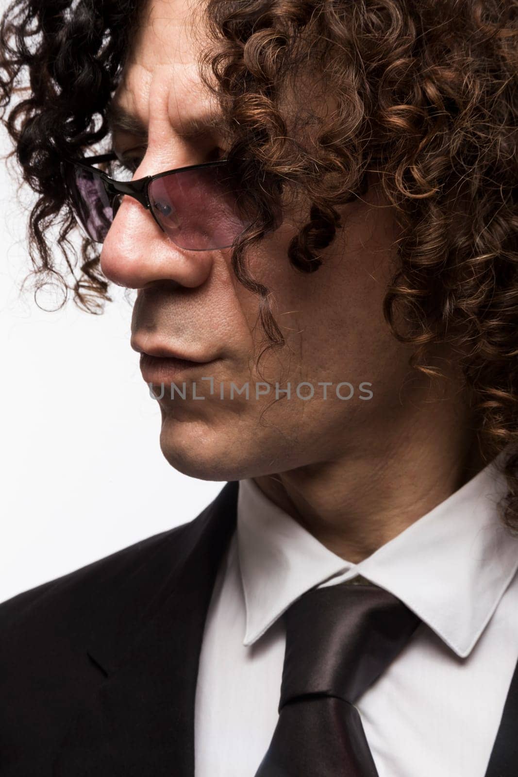 Cropped portrait of mediterranean looking man with curly hair wearing business suit and sun glasses