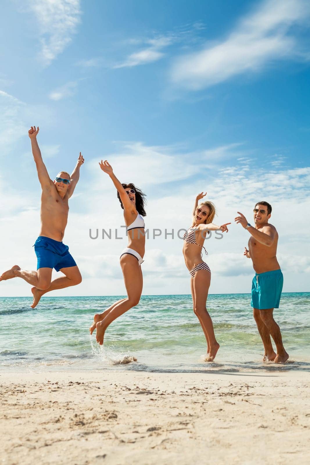 Group of laughing young people on the beach in summer holiday leisure lifestyle