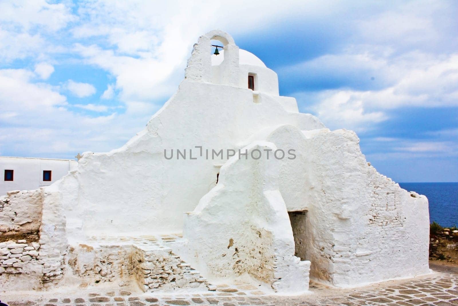 A single old white Greek church with a small church bell..