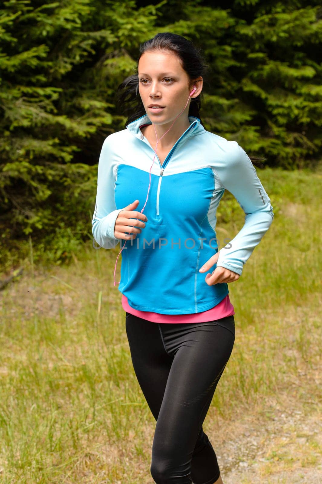 Sportive woman running  through meadow in countryside close-up