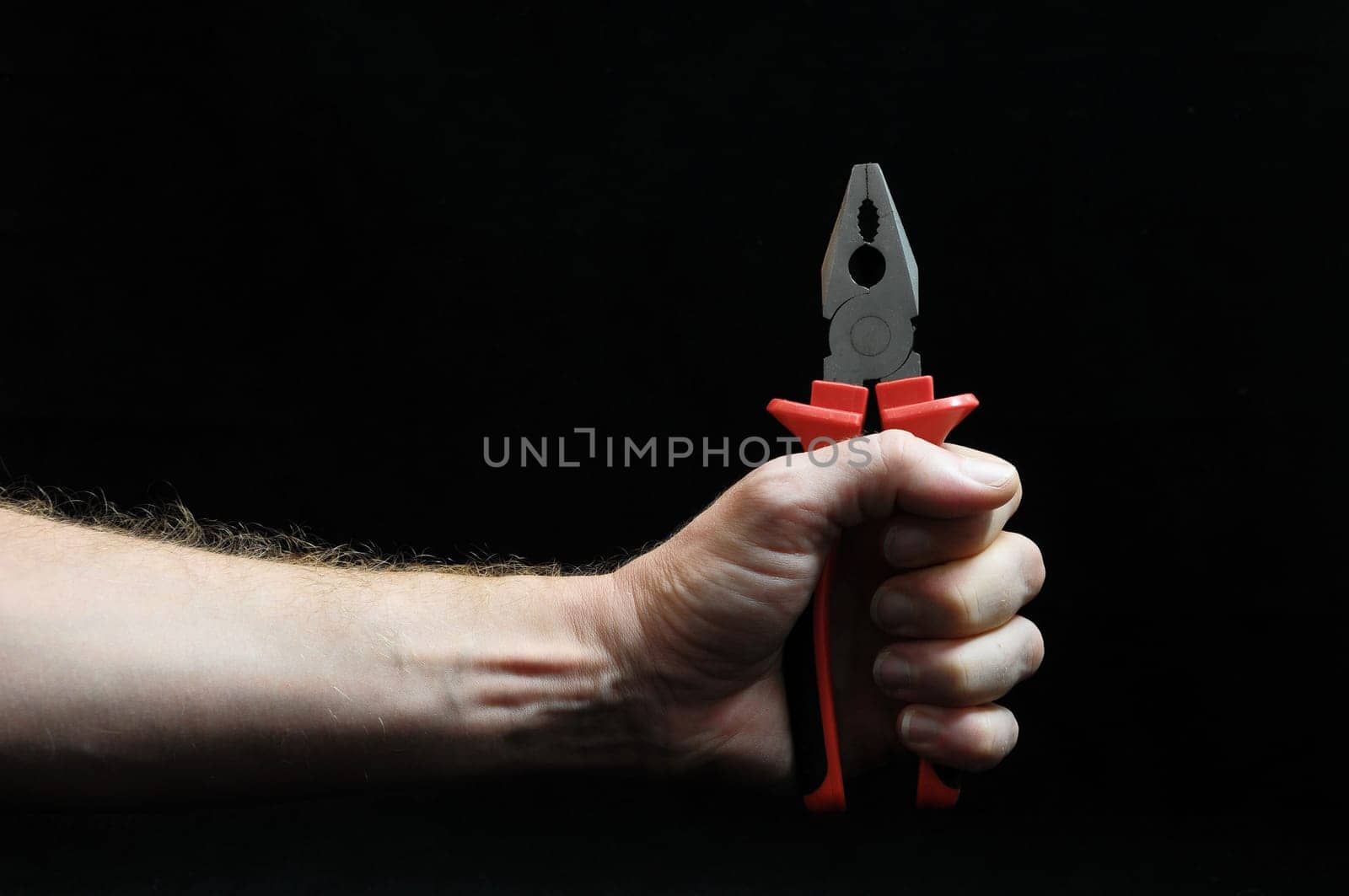 Pliers and a Hand on Black Background