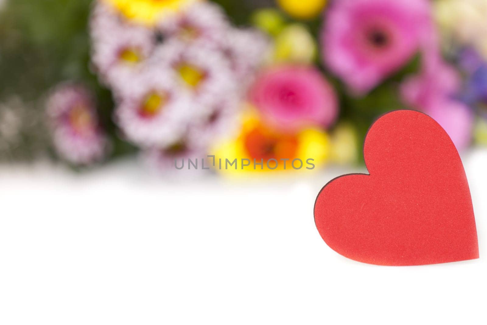 Red heart with text space in front of a bouquet of flowers