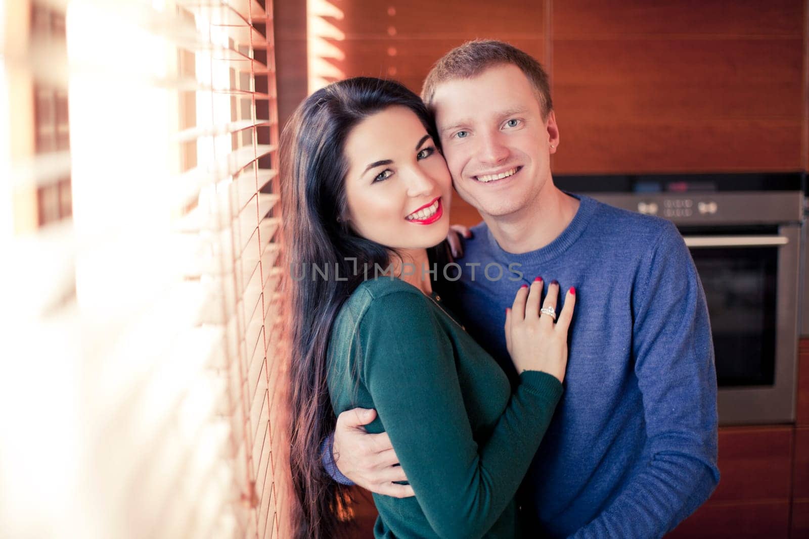 Young married couple in their house near the window louvers